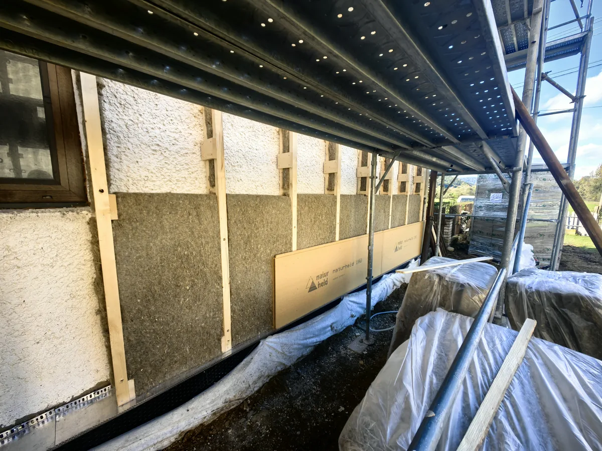 Fasáda starého domu na lešení s dreveným roštom, konopnými rohožami medzi latami a spodným radom drevovláknitých dosiek